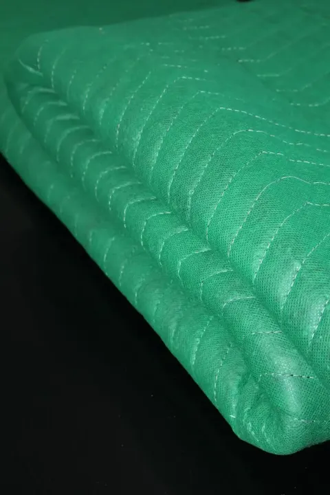 Folded green cotton moving pad in a warehouse