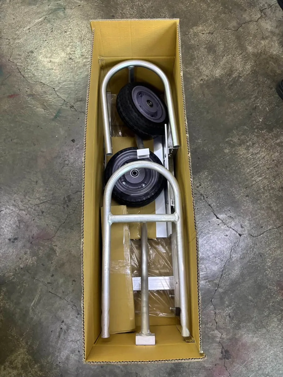 Convertible hand truck packed in a shipping box with wheel and handle parts visible