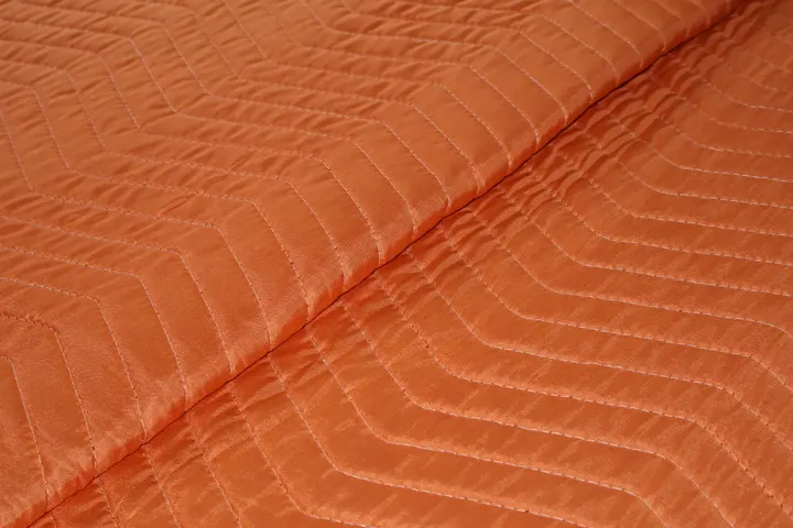 Stack of orange polyester moving pads in a warehouse